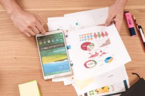 tablet on desk with printed out pie charts and graph