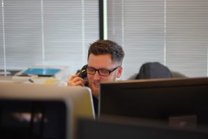 Man with glasses on phone call at desk