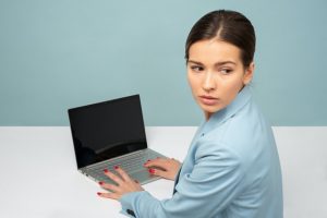 woman in blue shirt at laptop looking over her shoulder