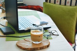 green table with a laptop, glasses and coffee