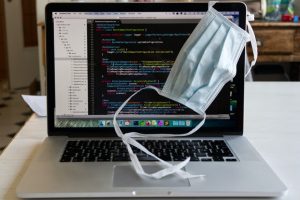 lap top with face mask laid over top corner